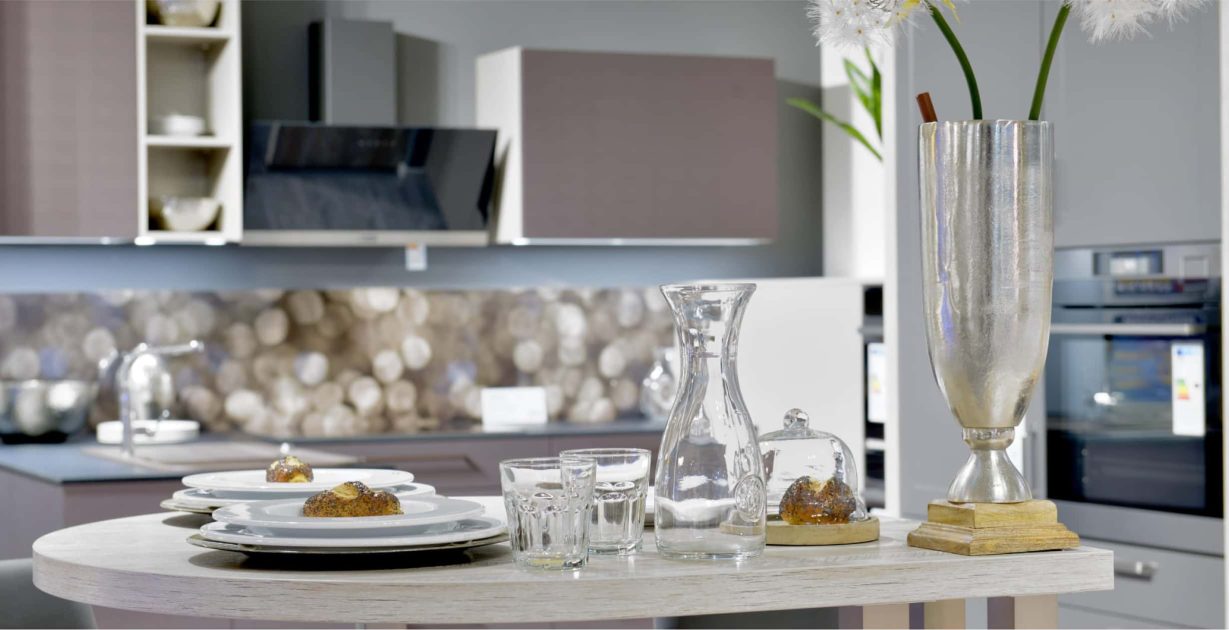 Kleiner Gedeckter Tisch im Vordergrund mit einer modernen Küche im Hintergrund