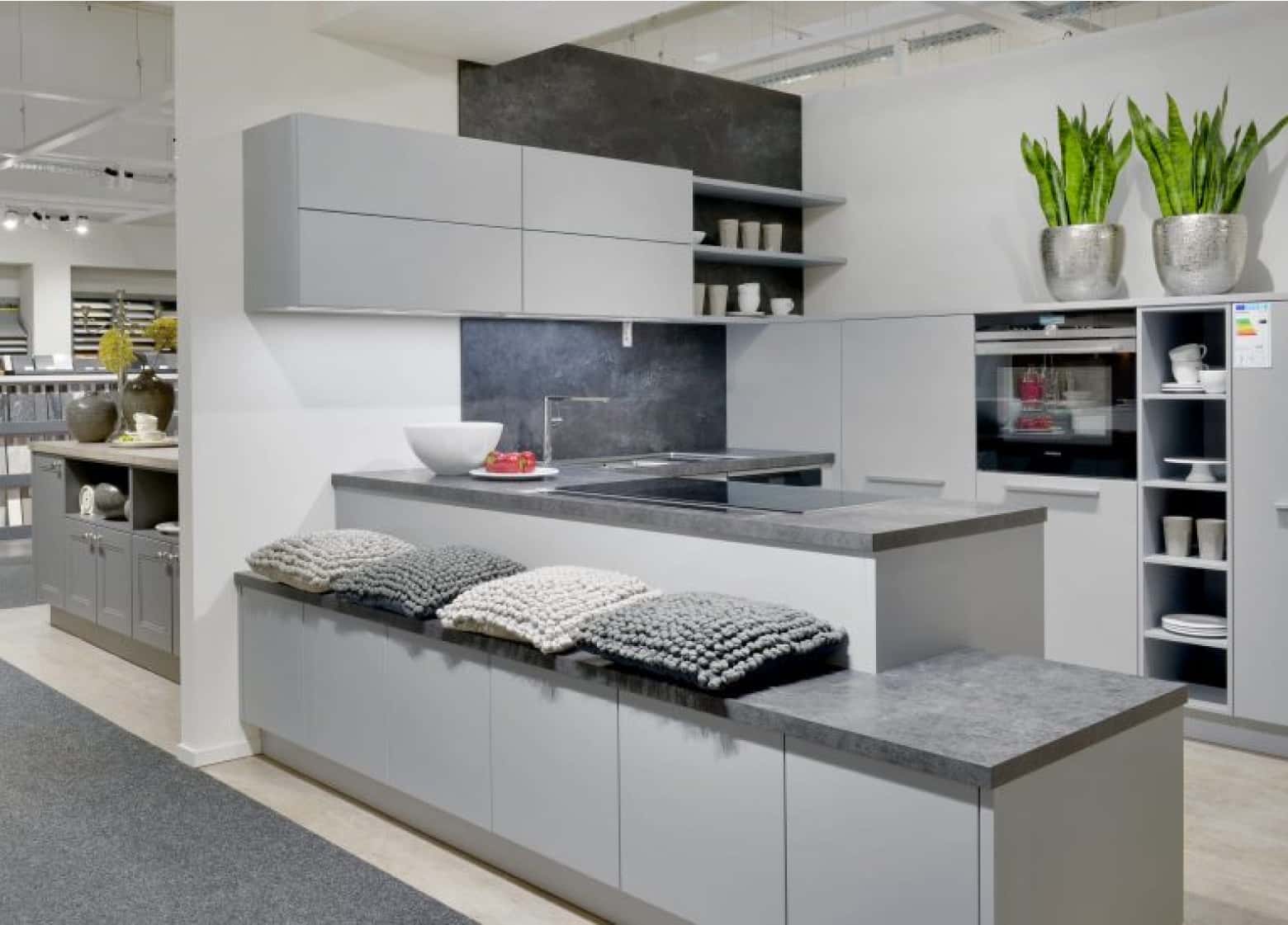 Moderne hellgraue Küche mit dunkelgrauer Arbeitsplatte mit abgesengter Ablage