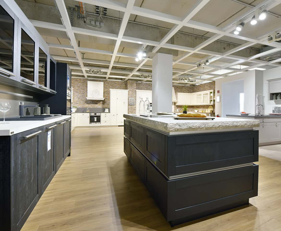 Moderne Designerküche mit großer Kücheninsel in schwarz und Naturstein Arbeitsplatte